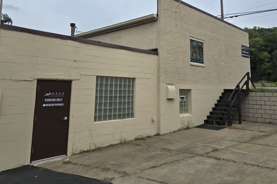 A brown door on the parking side of the building, with a sign reading Parking Only and an arrow pointing to the museum entrance.